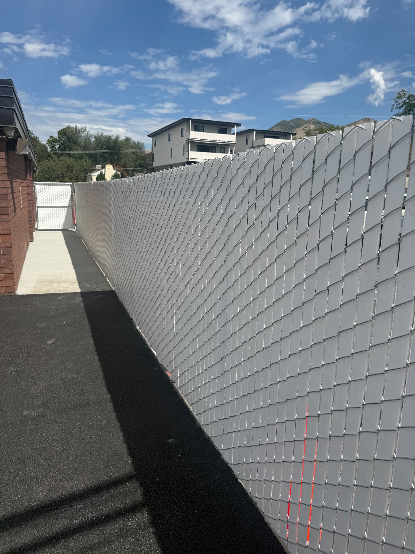 Chain link fence with white privacy slats along a commercial property