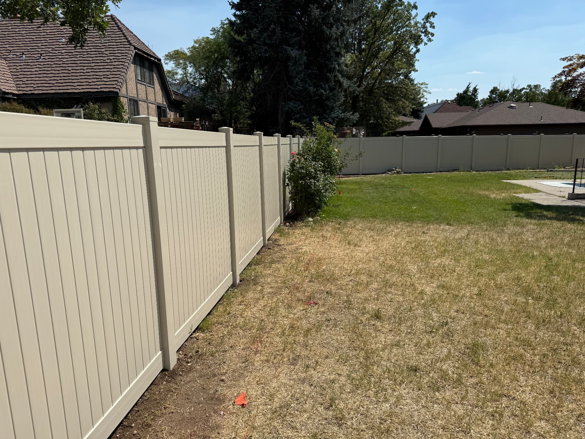 Tan vinyl privacy fence enclosing a Utah backyard