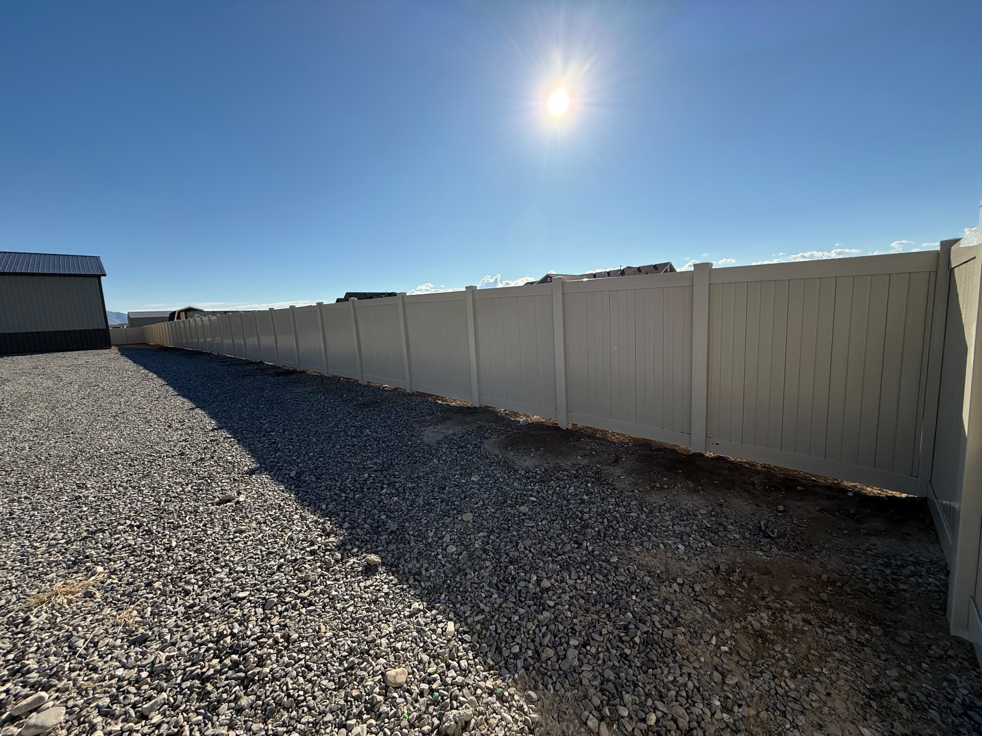 Long run of tan vinyl privacy fence installed at a Utah property