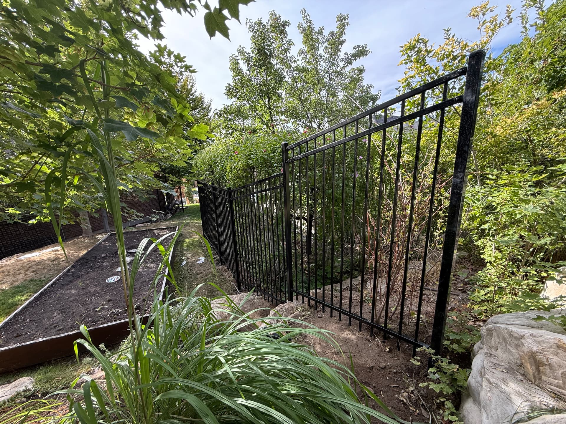 Black ornamental iron fence installed along a landscaped Utah backyard